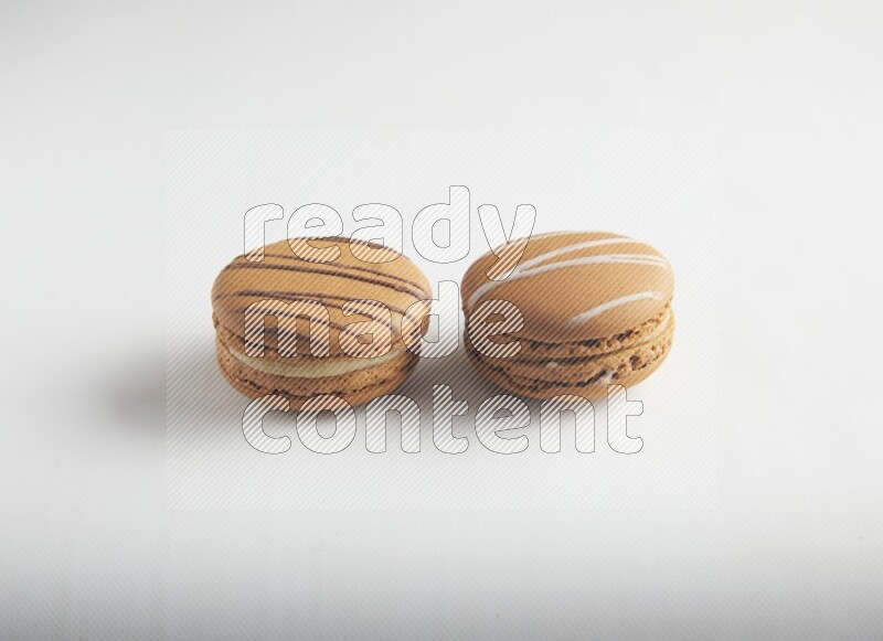 45º Shot of of two assorted Brown Irish Cream, and light brown  Almond Cream macarons on white background