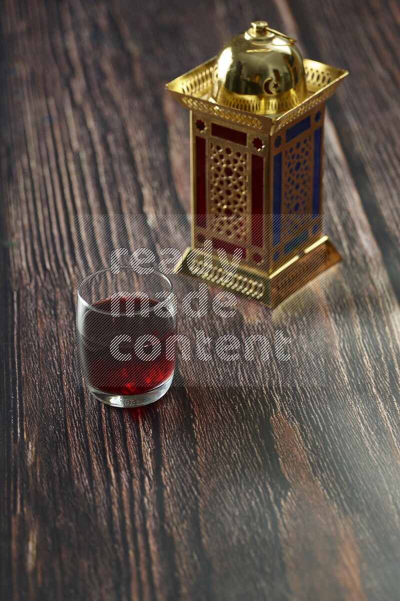 A golden lantern with different drinks, dates, nuts, prayer beads and quran on brown wooden background