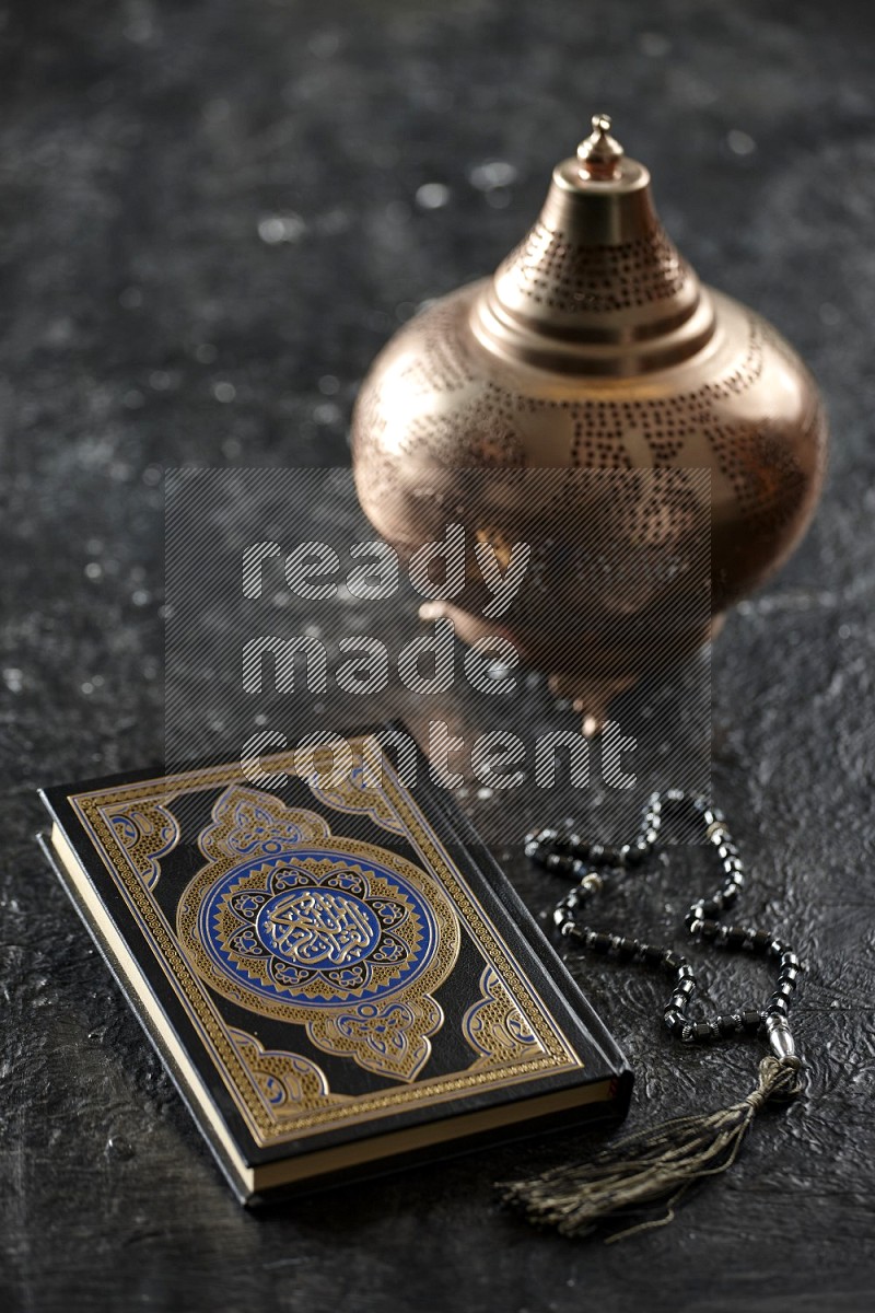 A golden lantern with different drinks, dates, nuts, prayer beads and quran on textured black background