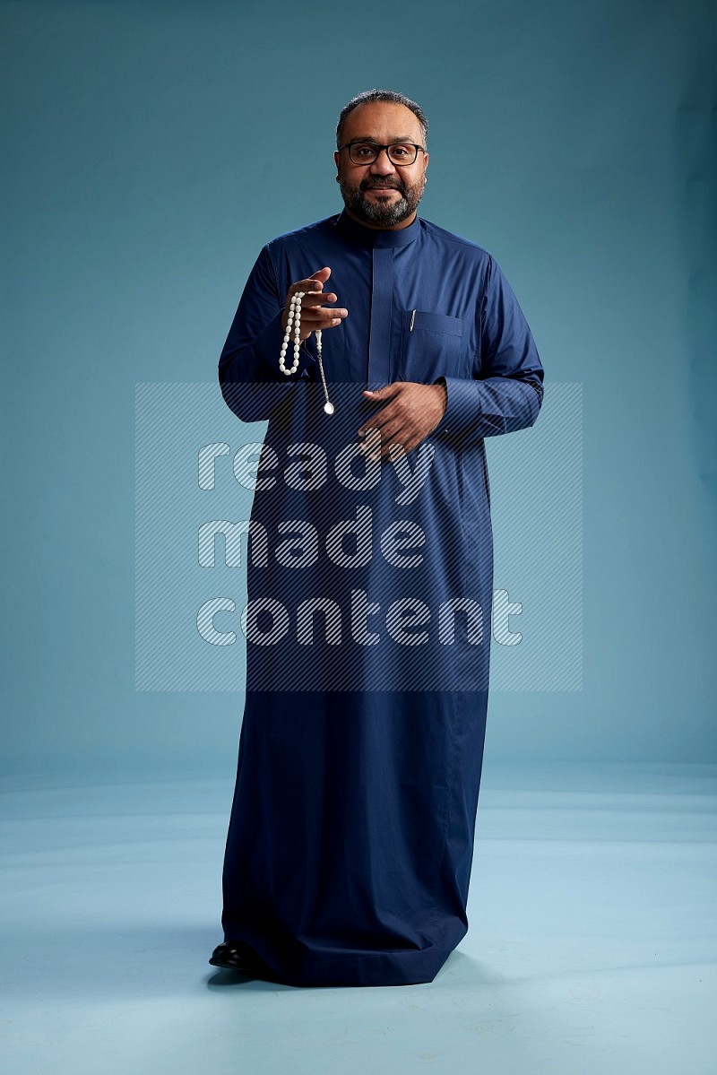 Saudi Man without shimag Standing Interacting with the camera on blue background