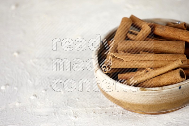 Cinnamon sticks in a ceramic bowl in different angles on white background