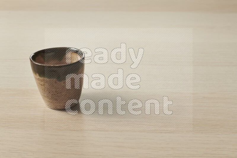 A pottery cup on light wooden background