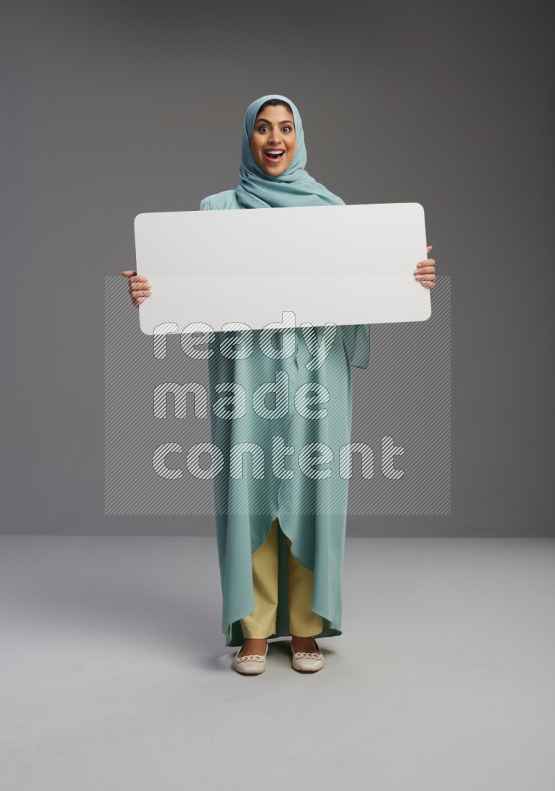 Saudi Woman wearing Abaya standing holding board on Gray background