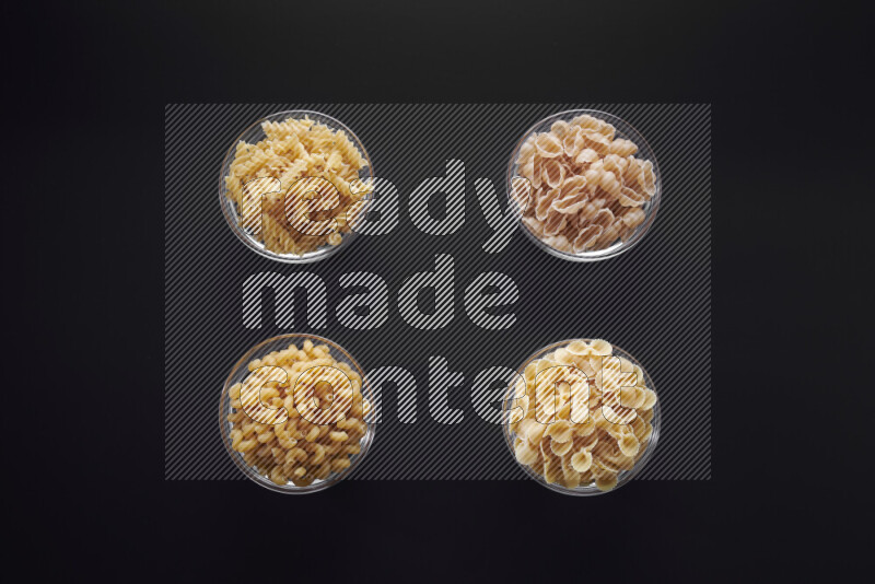 أنواع مختلفة من المعكرونة في وعاء زجاجي علي خلفية سوداء