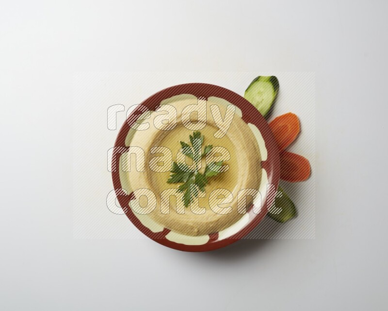 Hummus in a traditional plate garnished with parsley on a white background
