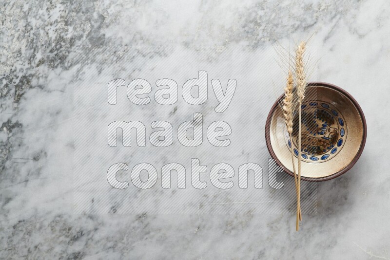 Wheat stalks on decorative pottery plate on grey marble background