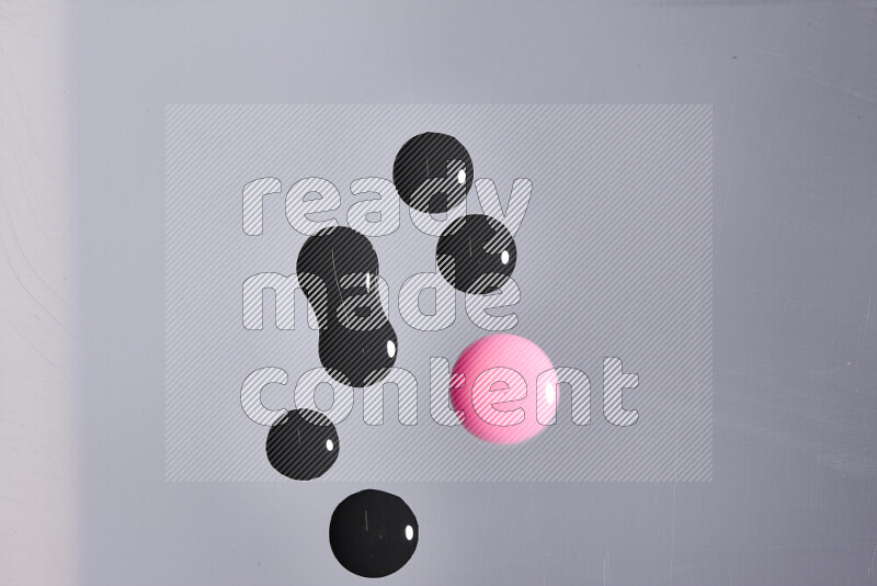 Close-ups of abstract pink and black paint droplets on the surface