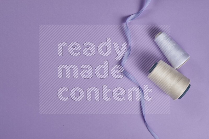 مجموعة من أدوات الخياطة والتفصيل بيضاء وأرجوانية اللون على خلفية أرجوانية