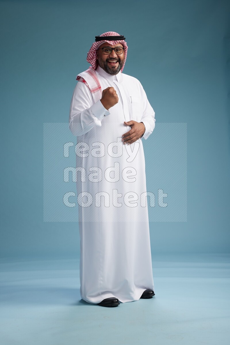 Saudi Man with shimag Standing Interacting with the camera on blue background