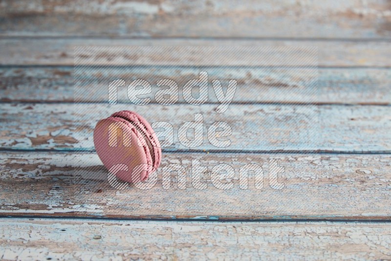 45º Shot of Purple Strawberry macaron on light blue wooden background