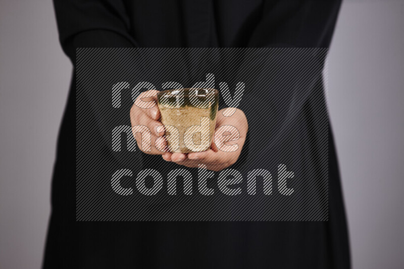 A woman in black abaya holding different pottery essentials in different positions
