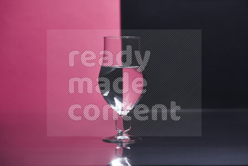 The image features a clear glassware filled with water, set against pink and black background