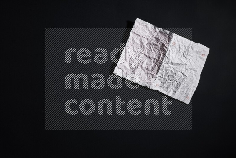 Crumpled notebook sheet on black background