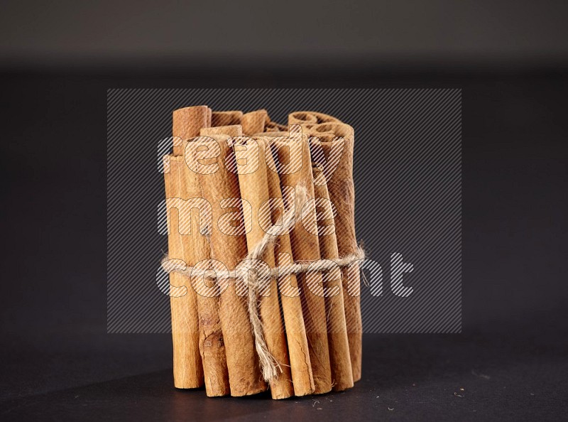 A bounded stack of cinnamon sticks on black background