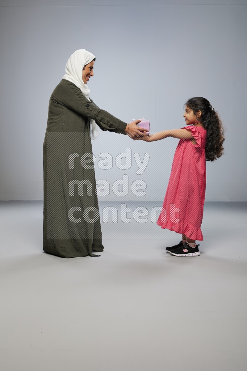 A girl giving a gift to her mother on gray background