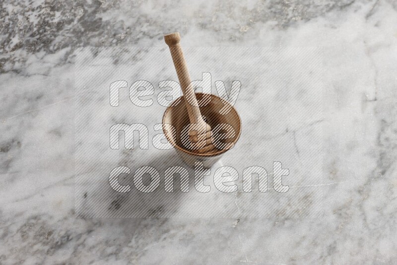 Decorative pottery bowl with wooden honey dipper in it on grey marble background