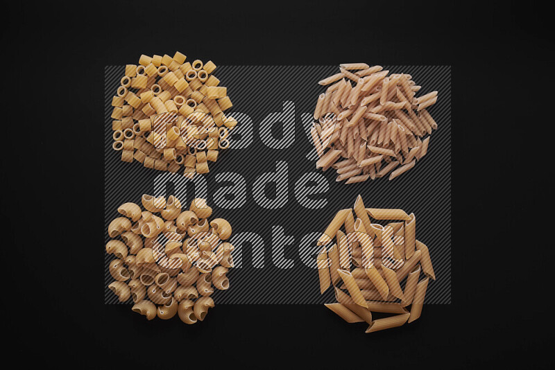 Different pasta types in bunches on black background