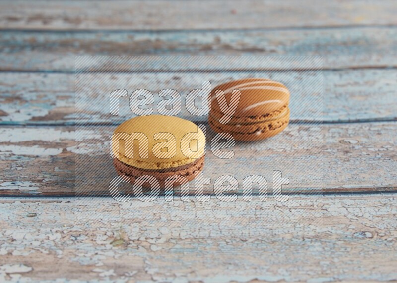 45º Shot of of two assorted Brown Irish Cream, and Yellow, and Brown Chai Latte macarons  on light blue background
