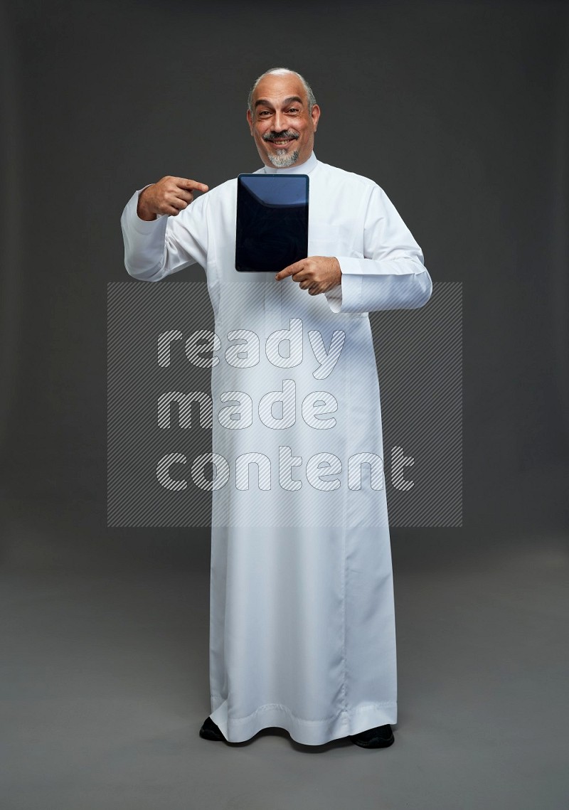 Saudi man without shomag Standing working on tablet on gray background