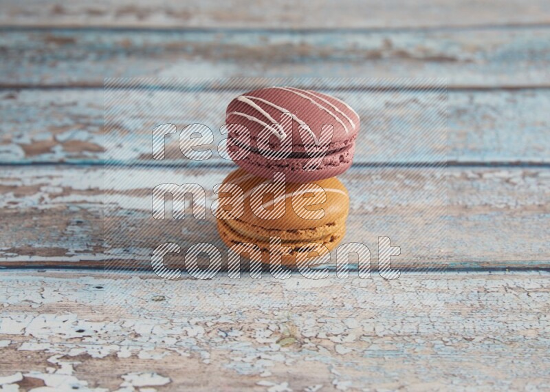 45º Shot of of two assorted Brown Irish Cream, and Red Poppy Flower macarons  on light blue background
