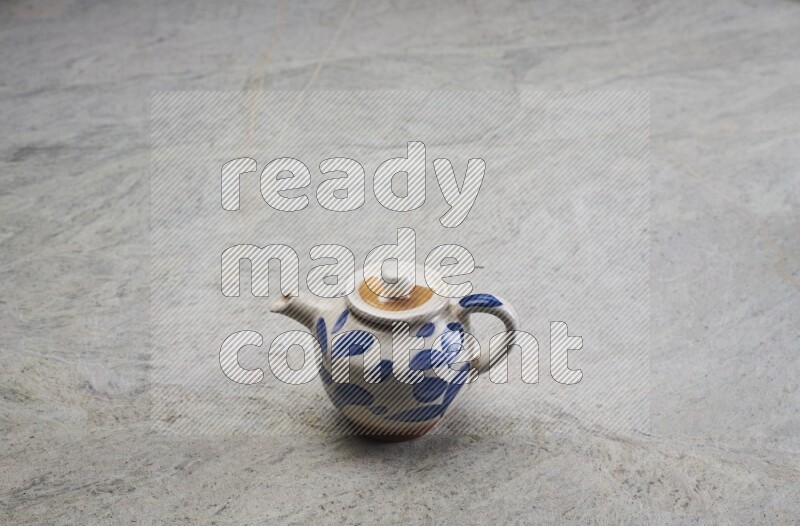 A pottery teapot on grey marble background