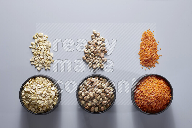 Legumes in pottery bowls on light grey background