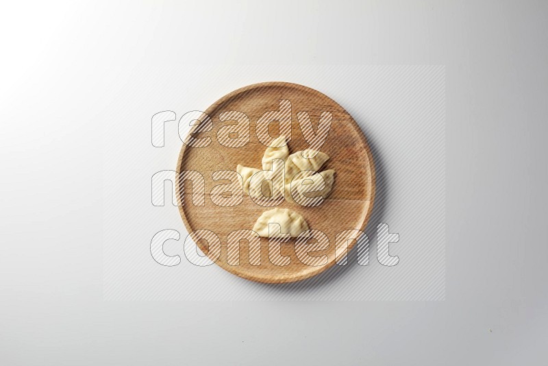 Five Sambosas on a wooden round plate on a white background