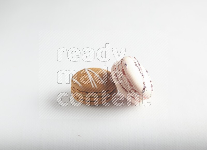 45º Shot of of two assorted Brown Irish Cream, and pink orange blossom macarons on white background
