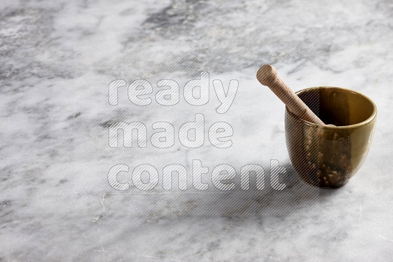 Multicolored Pottery Cup with wooden honey handle in it, on grey marble flooring, 45 degree angle