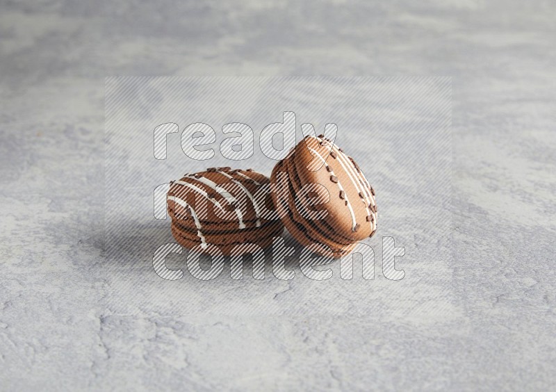 45º Shot of two Brown white marbleChocolate Caramel macarons  on white  marble background