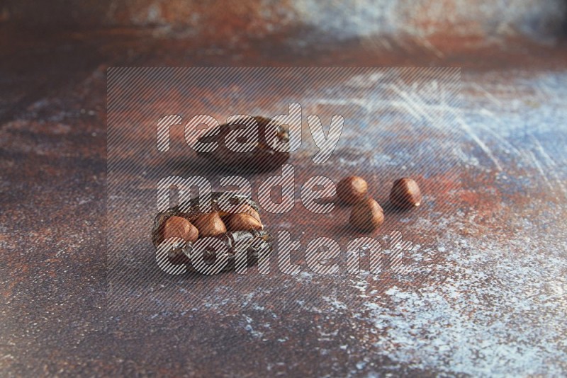 two hazelnut stuffed madjoul dates on a rustic reddish background