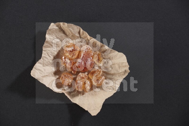 A crumpled piece of paper full of gum arabic on black flooring