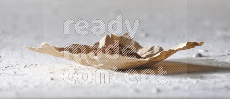 بودرة القرنفل في قطعة من الورق علي خلفية بيضاء