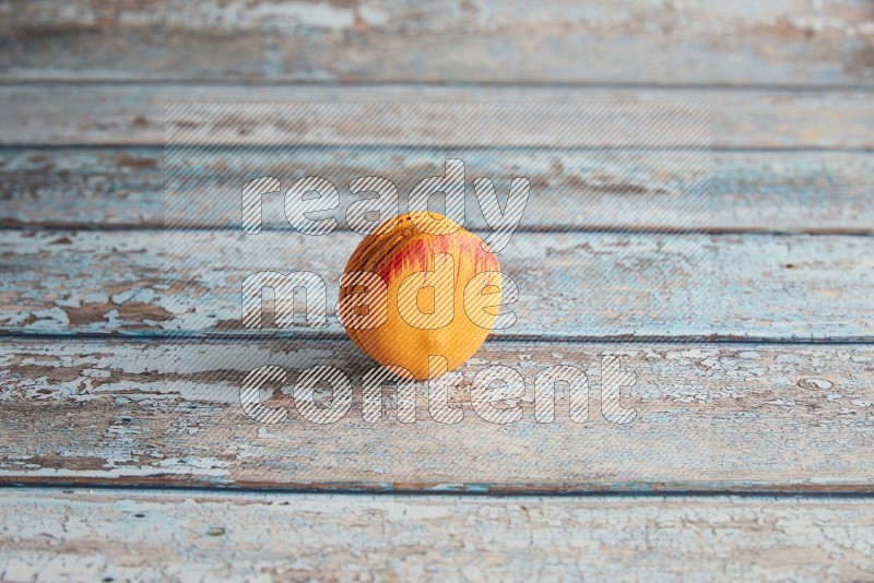 45º Shot of Orange Exotic macaron on light blue wooden background