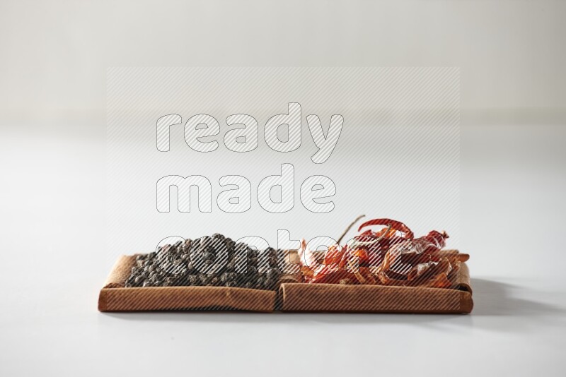 2 squares of cinnamon sticks full of red dried chilis and black pepper on white flooring