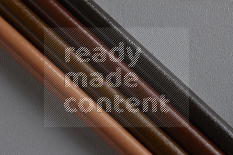 A collection of colored pencils arranged showcasing a gradient of brown hues on grey background