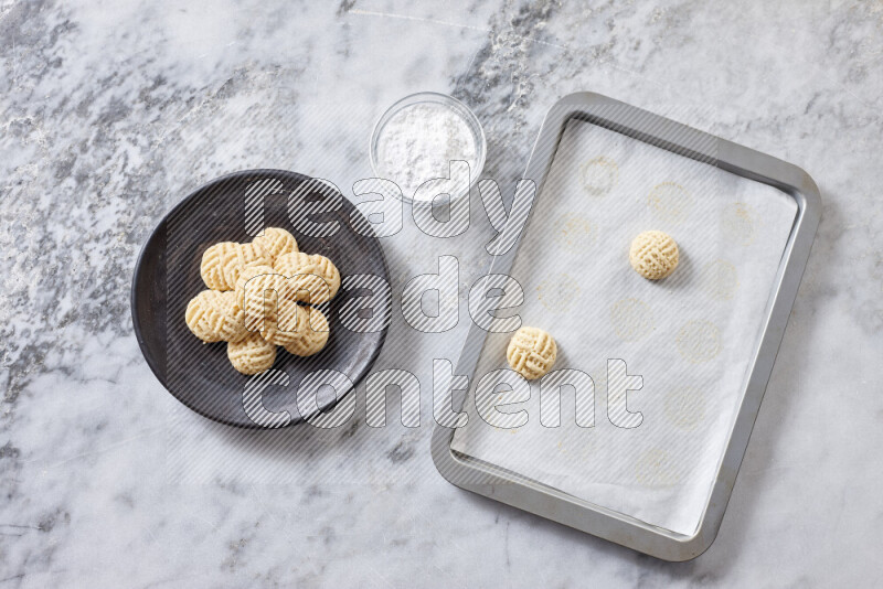 كحك خطوة بخطوة بمكوناته سمن، سكر، دقيق، سمسم، خميرة، ماء ونكهة الكحك على خلفية رخام رمادي