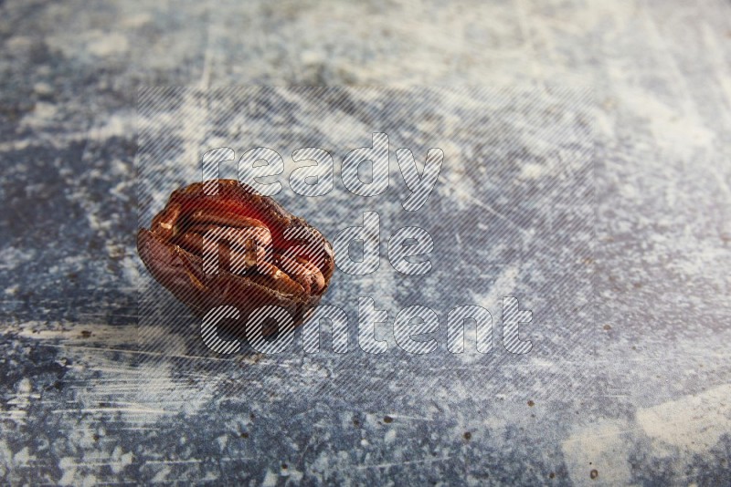 pecan stuffed madjoul date on a rustic blue background