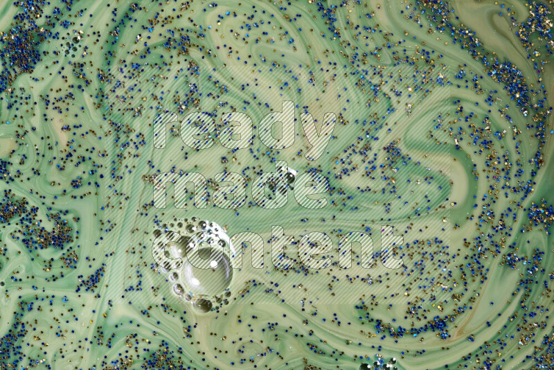 لقطة مقربة لبريق أزرق وذهبي متلألئ منتشر على خلفية من اللون الأخضر في حركات دائرية