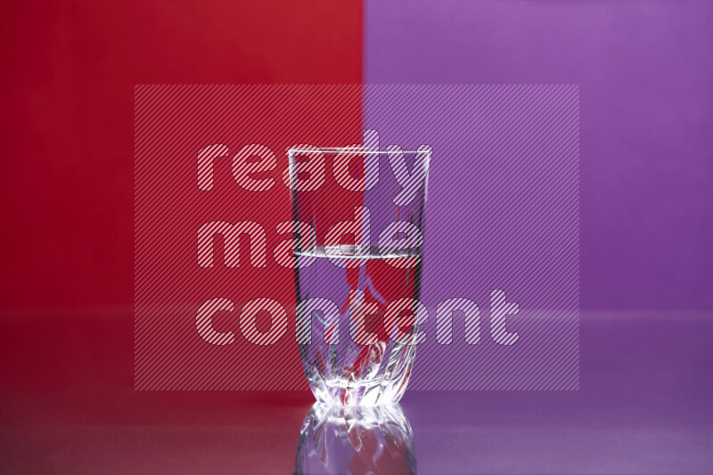 The image features a clear glassware filled with water, set against red and purple background