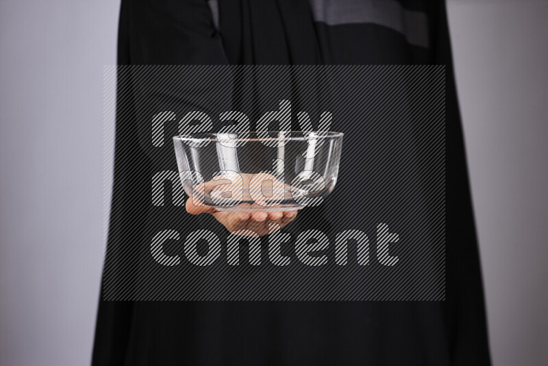 A woman in black abaya holding different glassware in different positions