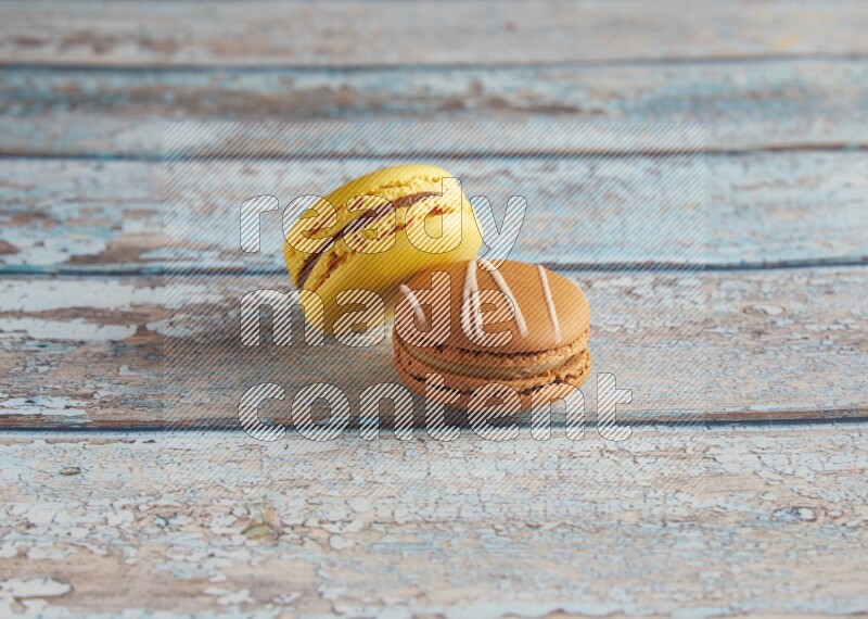 45º Shot of of two assorted Brown Irish Cream, and Yellow Lemon macarons on light blue background