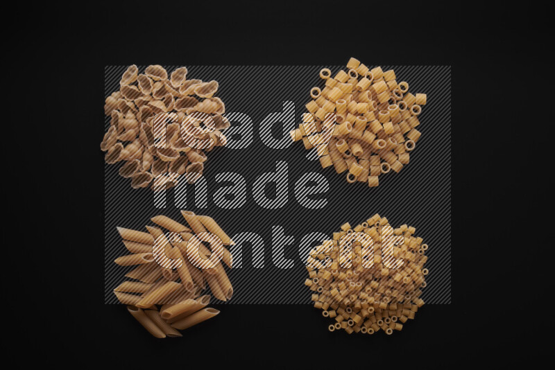 Different pasta types in bunches on black background