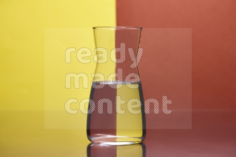 The image features a clear glassware filled with water, set against yellow and dark orange background