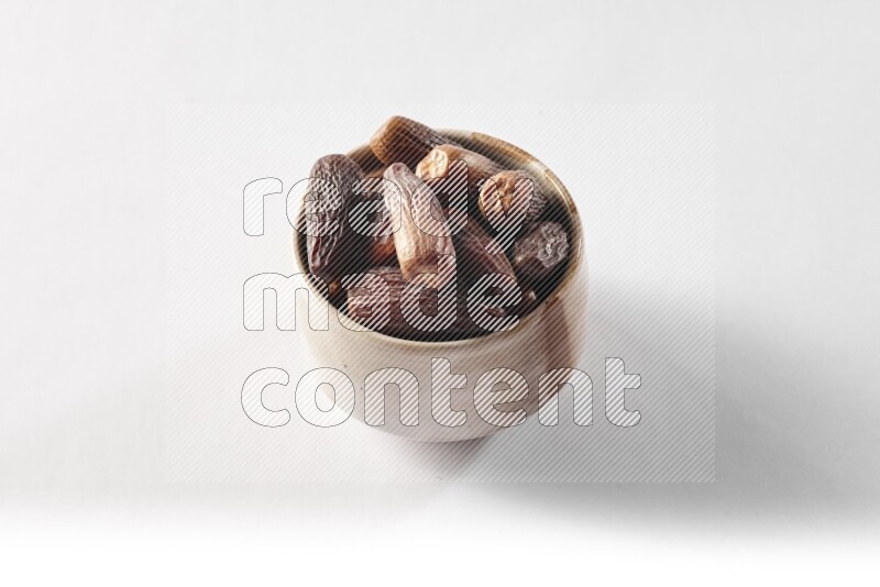 Dates in a beige pottery bowl on white background