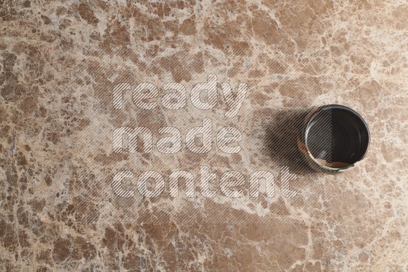 A multicolored pottery bowl on beige marble background