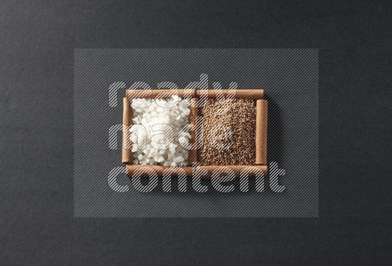 مربعان من أعواد القرفة ممتلئان بحبوب الخردل والملح الأبيض علي خلفية سوداء