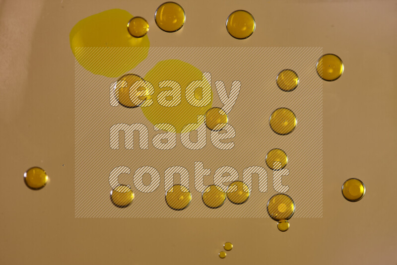 Close-ups of abstract yellow watercolor drops on oil Surface on yellow background