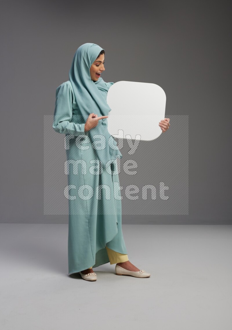 Saudi Woman wearing Abaya standing holding social media sign on Gray background