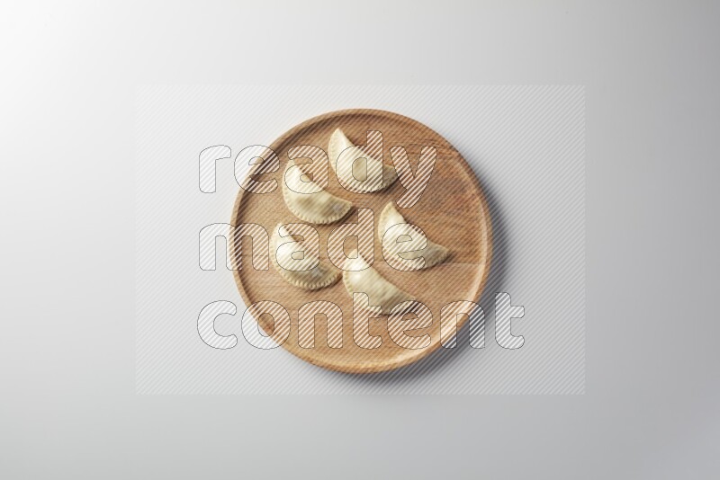 Five Sambosas on a wooden round plate on a white background
